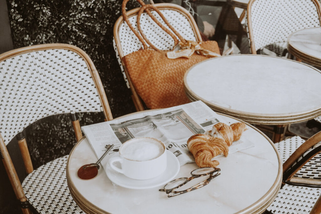 cafe tablescape in paris with a coffee croissant and newspaper