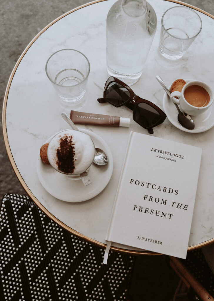 Wayfarer linen travel journal sitting at a cafe in paris with a cappuccino