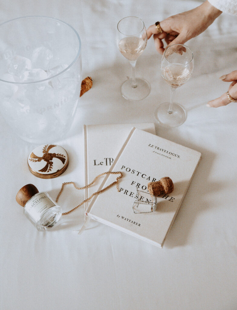 flatlay of linen journals and notebooks on bed with champagne